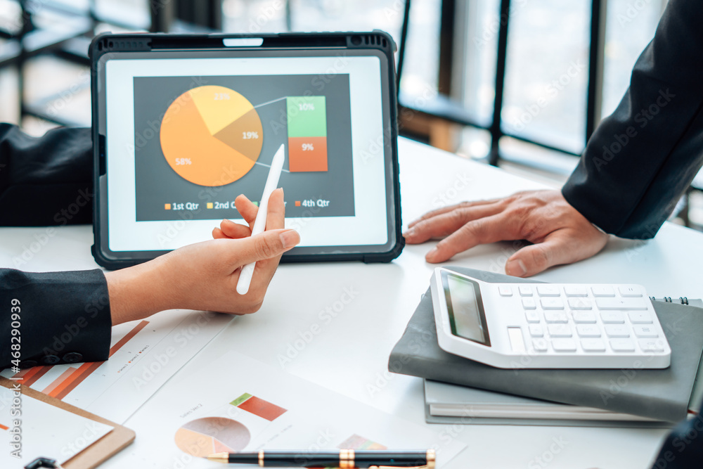 Two businessmen are together analyzing the financial data graph and pointing to the laptop computer screen. Two businessmen are together analyzing the financial data graph and pointing to the laptop computer screen.