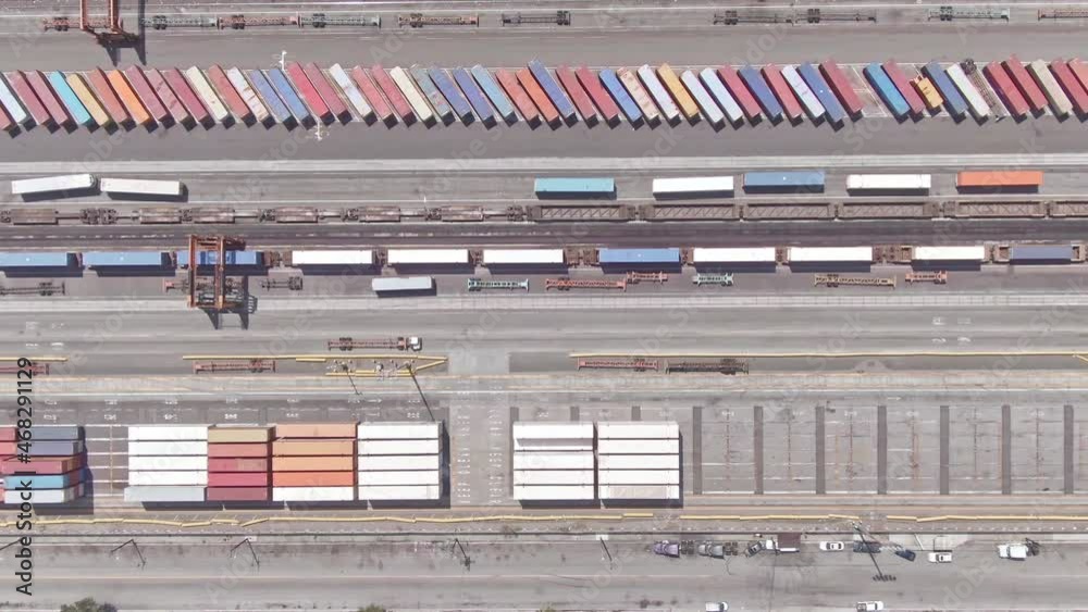 Aerial view trucks moving shipping cargo containers, freight trains at railway port. Flying over trains at depot. Shipment from China. Drone shot 4k. Global import export transportation. Aerial view trucks moving shipping cargo containers, freight trains at railway port. Flying over trains at depot. Shipment from China. Drone shot 4k. Global import export transportation.