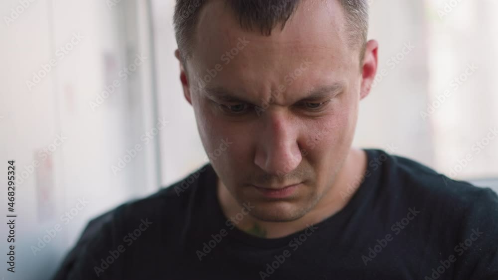 Worried middle aged gentleman in black t-shirt looks at information on phone spending time in light spacious office extreme close view slow motion