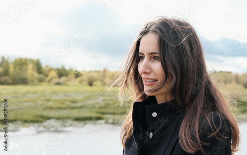 middle east woman with long brown hair looking aside and smiling. outdoor portrait of beautiful asian or mixed race woman.