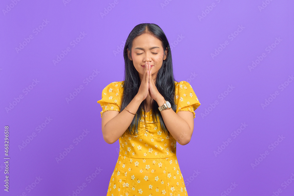 Attractive young Asian woman hand in pray near mouth on purple background Attractive young Asian woman hand in pray near mouth on purple background