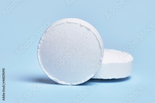 Macro shot of two white medical pills on bright blue background