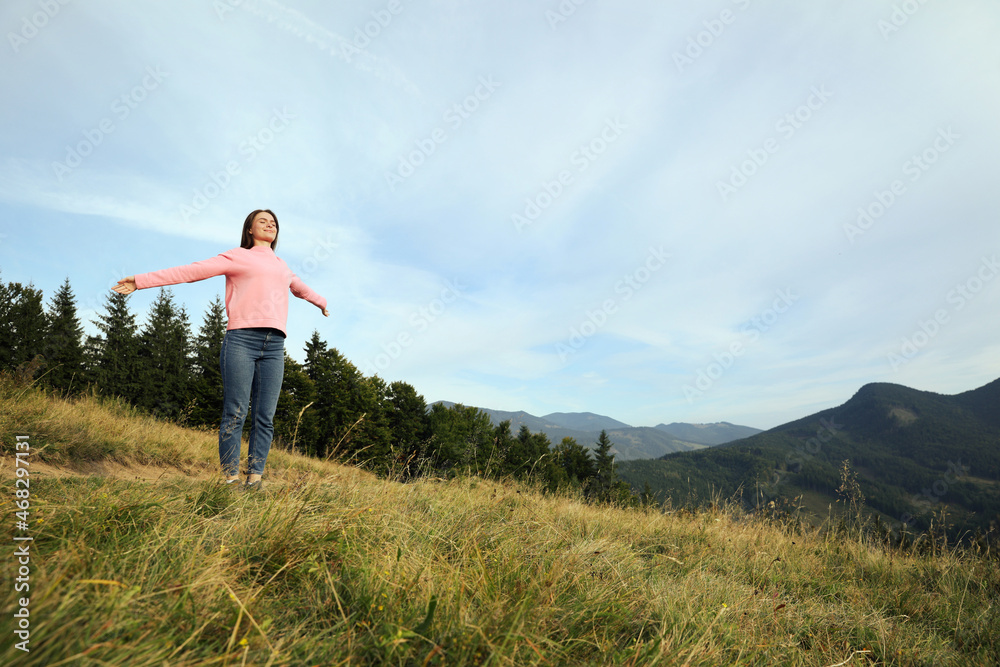 Young woman enjoying mountain landscape. Space for text