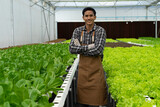 Happy young Asian farmer agronomist farmer smiling with hydroponic fresh green vegetables produce in greenhouse garden nursery farm, smart farming, agriculture business concept