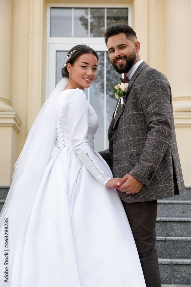 Young bride and groom on stairs outdoors. Wedding couple