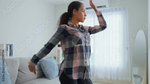 Active woman Latino listen to music and dance on floor in living room.  photo