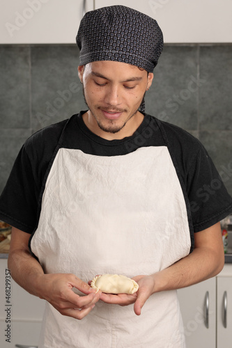 Young Latin American man closing an empanada. Traditional South American food, Argentinean, Uruguayan. Entrepreneur. Cook at work.