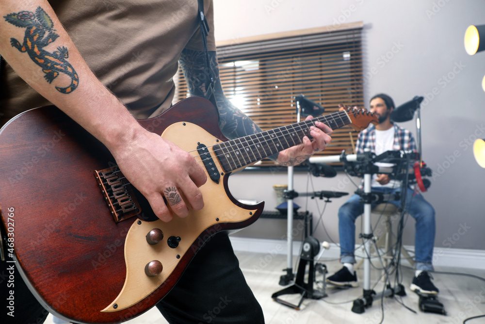 Man playing electric guitar during rehearsal in studio, closeup. Music band practice - obrazy, fototapety, plakaty 