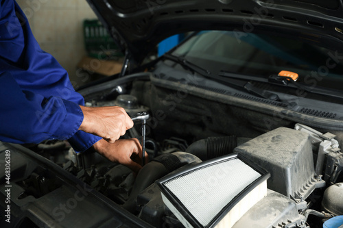 Professional mechanic fixing modern car at automobile repair shop, closeup