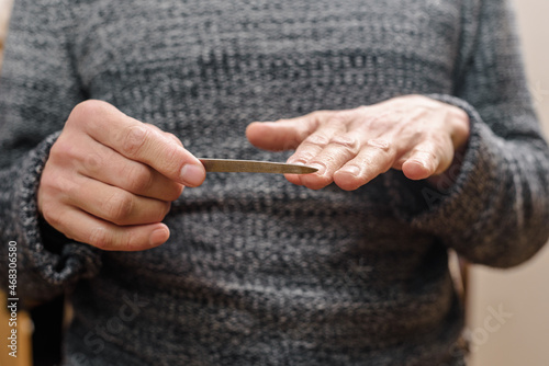 Young man polishing his fingernails with nail file at home, male self-care