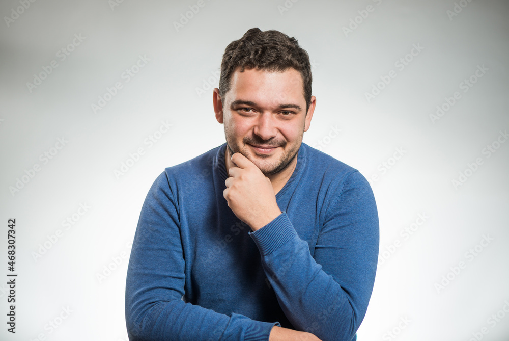 young positive man portrait in blue sweater at studio background