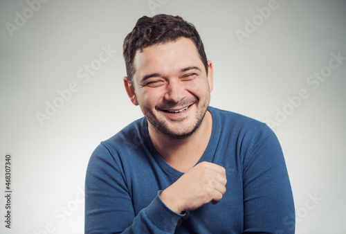 young laughing man portrait in blue sweater at studio background