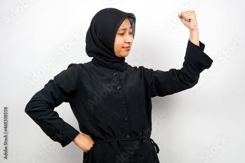 Beautiful asian young muslim woman with raised muscles, strength sign arms, isolated on white background