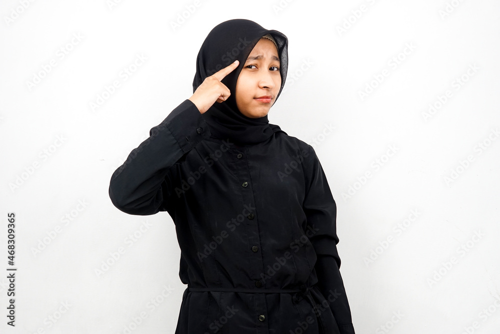 Beautiful young asian muslim woman with finger pointing at head, thinking smart, isolated on white background