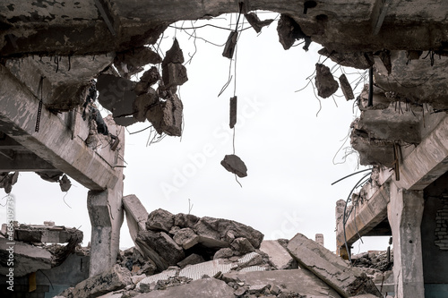 Concrete fragments on metal fittings with the remains of a building against a gray sky. Background