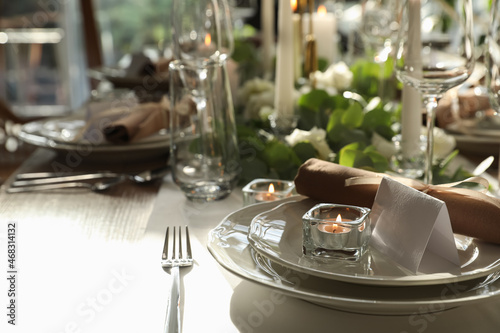 Elegant table setting with beautiful floral decor and burning candle. Space for text
