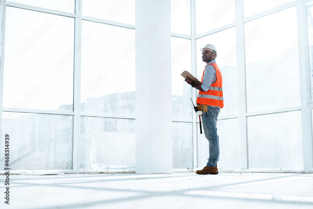 Foreman at work on construction site checking his notes on clipboard