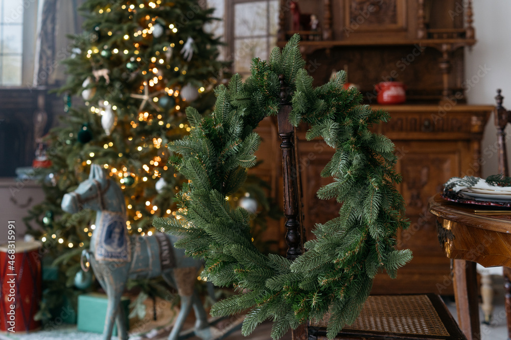 Christmas wreath on the chair and christmas tree at background