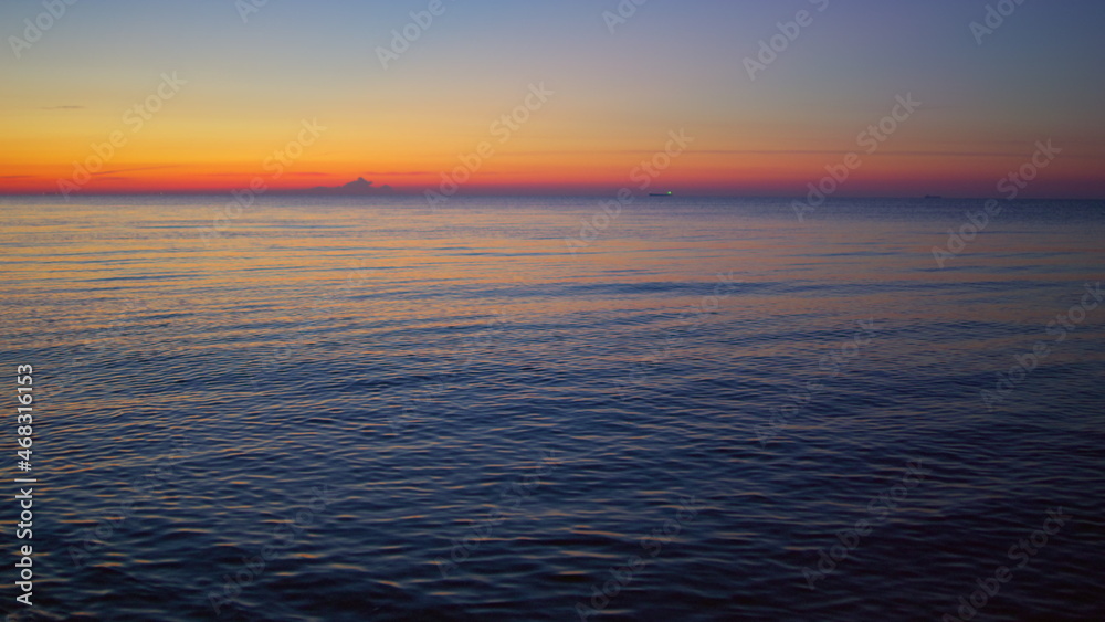 Sea sunset reflecting at water surface in evening dawn. Calm blue ocean waves