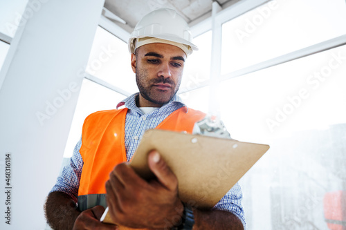 Foto Foreman at work on construction site checking his notes on clipboard