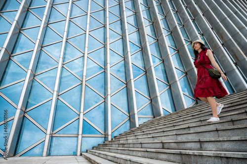 Quadro su tela Asian woman in red dress at modern building, female girl with urban city lifesty