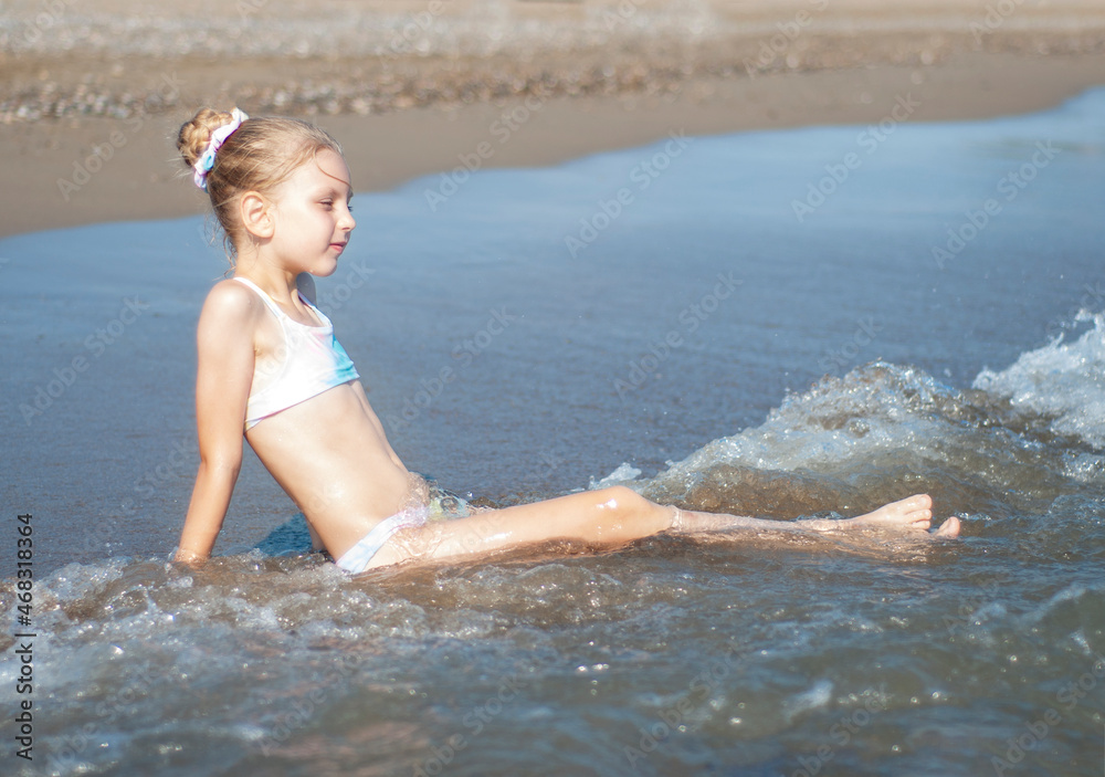 Little girl playing on the beach by the sea