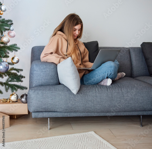 Teenage girl with laptop sitting on sofa in living room