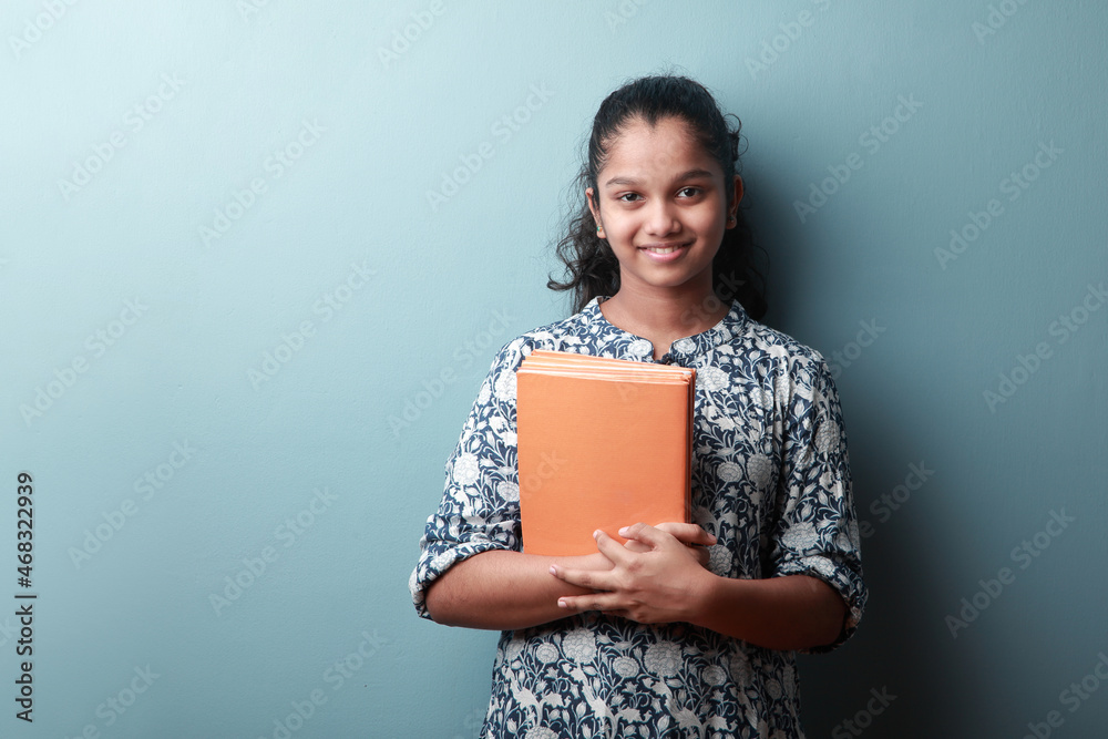 Happy girl of Indian ethnicity holding note books in her hand Happy girl of Indian ethnicity holding note books in her hand