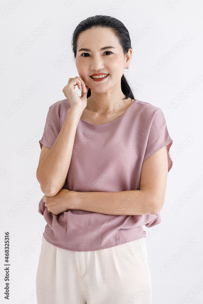 Portrait closeup studio shot of Asian young happy friendly beautiful female model in casual pink outfit standing smiling looking at camera hold hand at chin crossed arm in front white wall background Portrait closeup studio shot of Asian young happy friendly beautiful female model in casual pink outfit standing smiling looking at camera hold hand at chin crossed arm in front white wall background