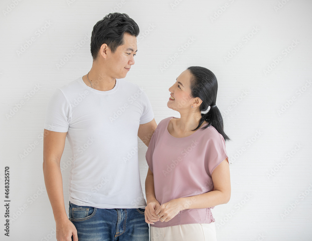 Portrait shot of Asian young happy friendly handsome male and beautiful female parent lover couple models in casual outfit standing smiling looking at camera together in front white wall background Portrait shot of Asian young happy friendly handsome male and beautiful female parent lover couple models in casual outfit standing smiling looking at camera together in front white wall background