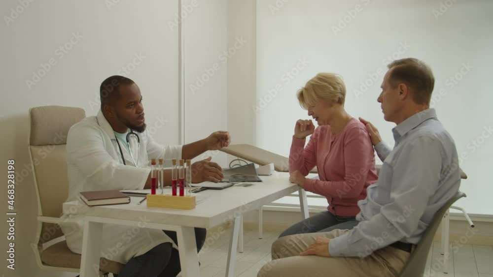 Upset crying sick charming middle aged woman consoled by beloved husband, receiving bad news about health status from empathetic african american male doctor during visit at medical clinic. Upset crying sick charming middle aged woman consoled by beloved husband, receiving bad news about health status from empathetic african american male doctor during visit at medical clinic.