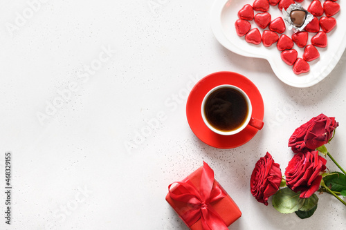 Valentine's day coffee, red gift and red roses on white background. Romantic greeting card for dating. View from above. Copy space.