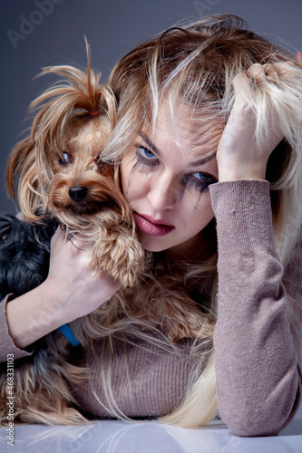 Portrait of crying woman with small dog. Vertical image.