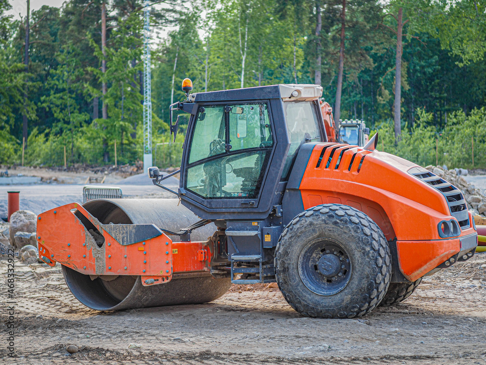 Road construction. Large rolling machinery paving a road to a distant city Road construction. Large rolling machinery paving a road to a distant city