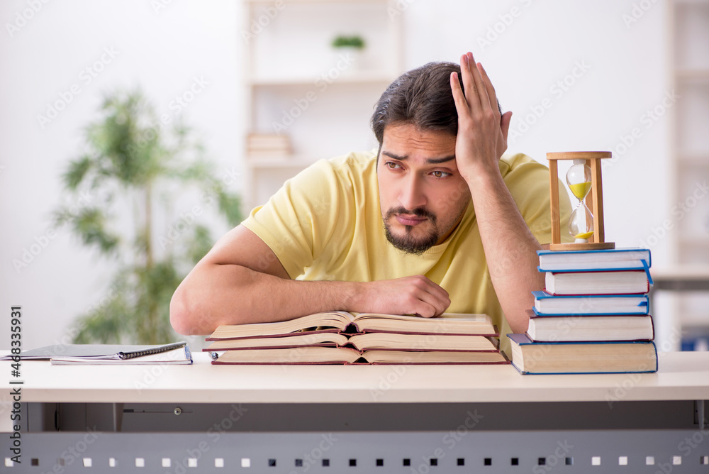 Obraz premium Young male student preparing for exams in time management concep