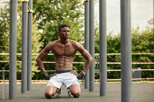 Portrait of black male working out outdoors in a park. He is using a chest machine.