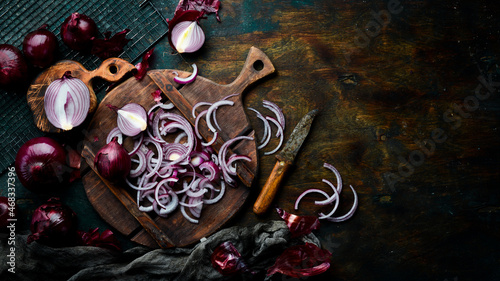 Purple onion. Fresh chopped onions on a wooden board. Top view. On a black stone background.