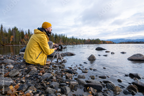 Professional nature photographer taking photo of lake wearing bright yellow coat