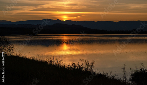 Sunset over mountains. Reflection on water surface. Colorful twilight sky