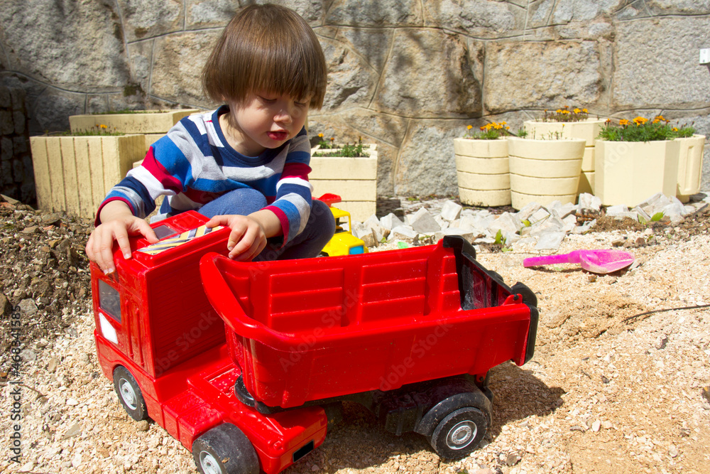 little three year old boy playing in the sand with a digger and dump truck.
little three year old boy playing in the sand with a digger and dump truck.
