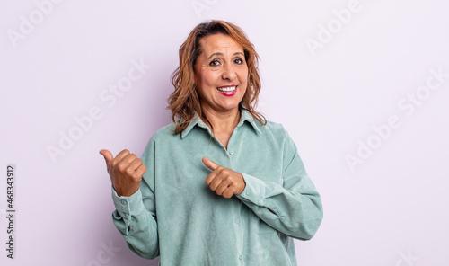 Schilderij op canvas middle age woman smiling cheerfully and casually pointing to copy space on the s