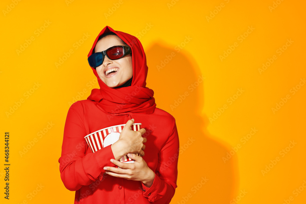 Obraz premium woman in red hijab 3d glasses technology watching movie popcorn yellow background