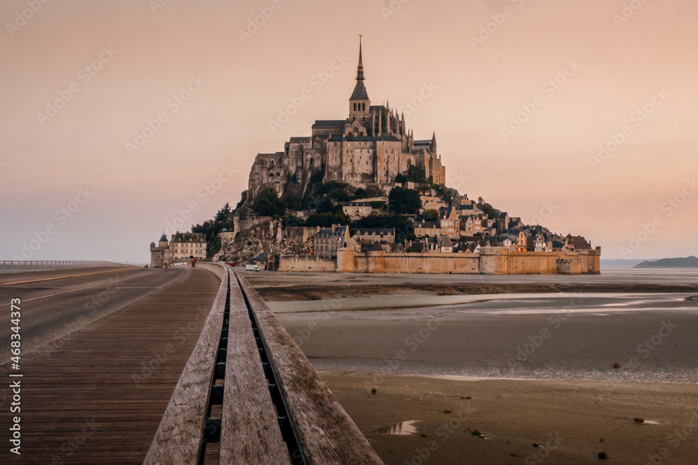 View of famous Mont Saint Michel tidal island and jetty bridge at a beautiful sunrise time in Normandy, Northern France