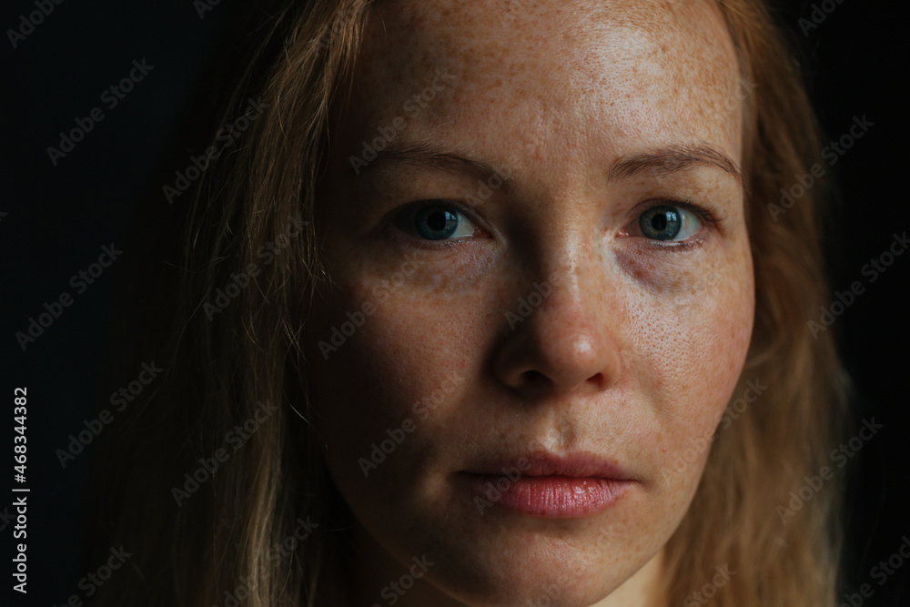 Beautiful woman with read hair and freckles. Close up portrait against black background Beautiful woman with read hair and freckles. Close up portrait against black background