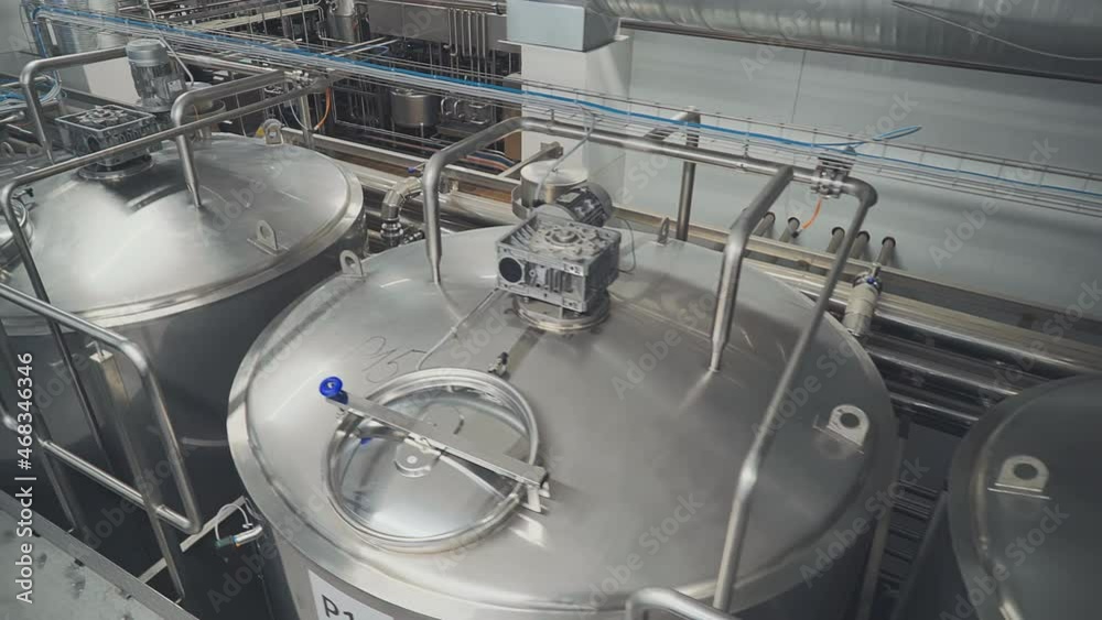 Moving through the Industrial Dairy Production Facility. Huge Milk Containers at Modern Conveyor