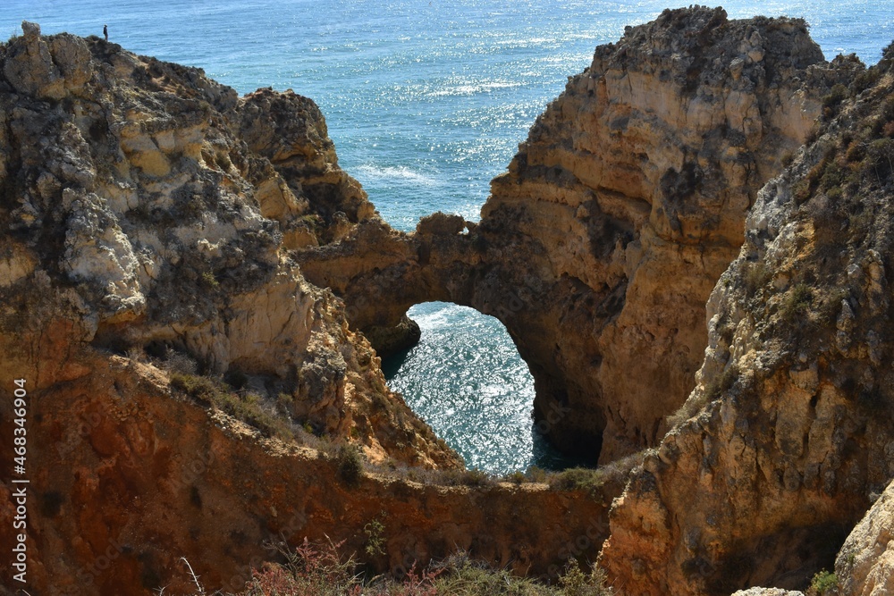 
An unidentified tourist in the distance, Yellow rocks and the sea in the Algarve, Portugal
