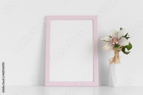 Pink frame mockup with a orchid on the white table.