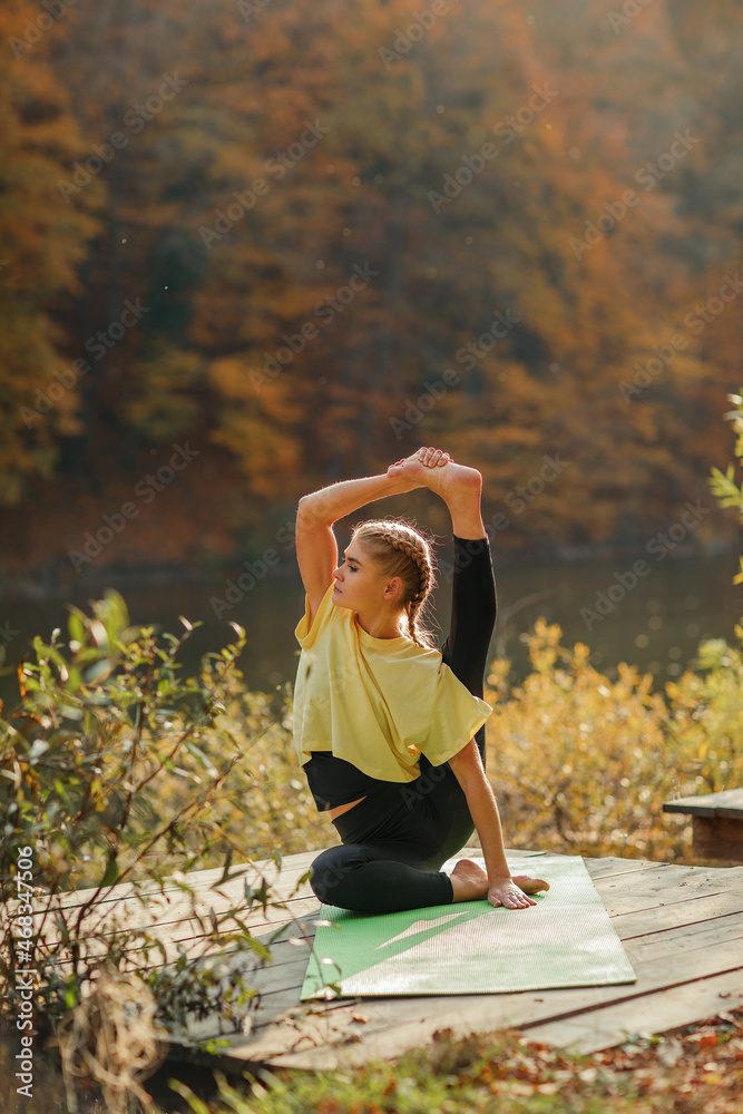 Obraz premium A young beautiful blonde woman does yoga in nature