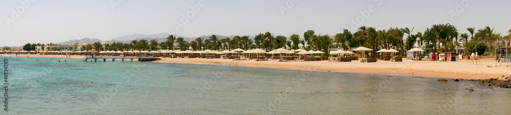 Hurghada, Egypt - September 22, 2021: Panoramic view of the Red Sea coast. People are relaxing, swimming on the sandy beach with umbrellas and sun loungers.