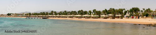 Hurghada, Egypt - September 22, 2021: Panoramic view of the Red Sea coast. People are relaxing, swimming on the sandy beach with umbrellas and sun loungers.